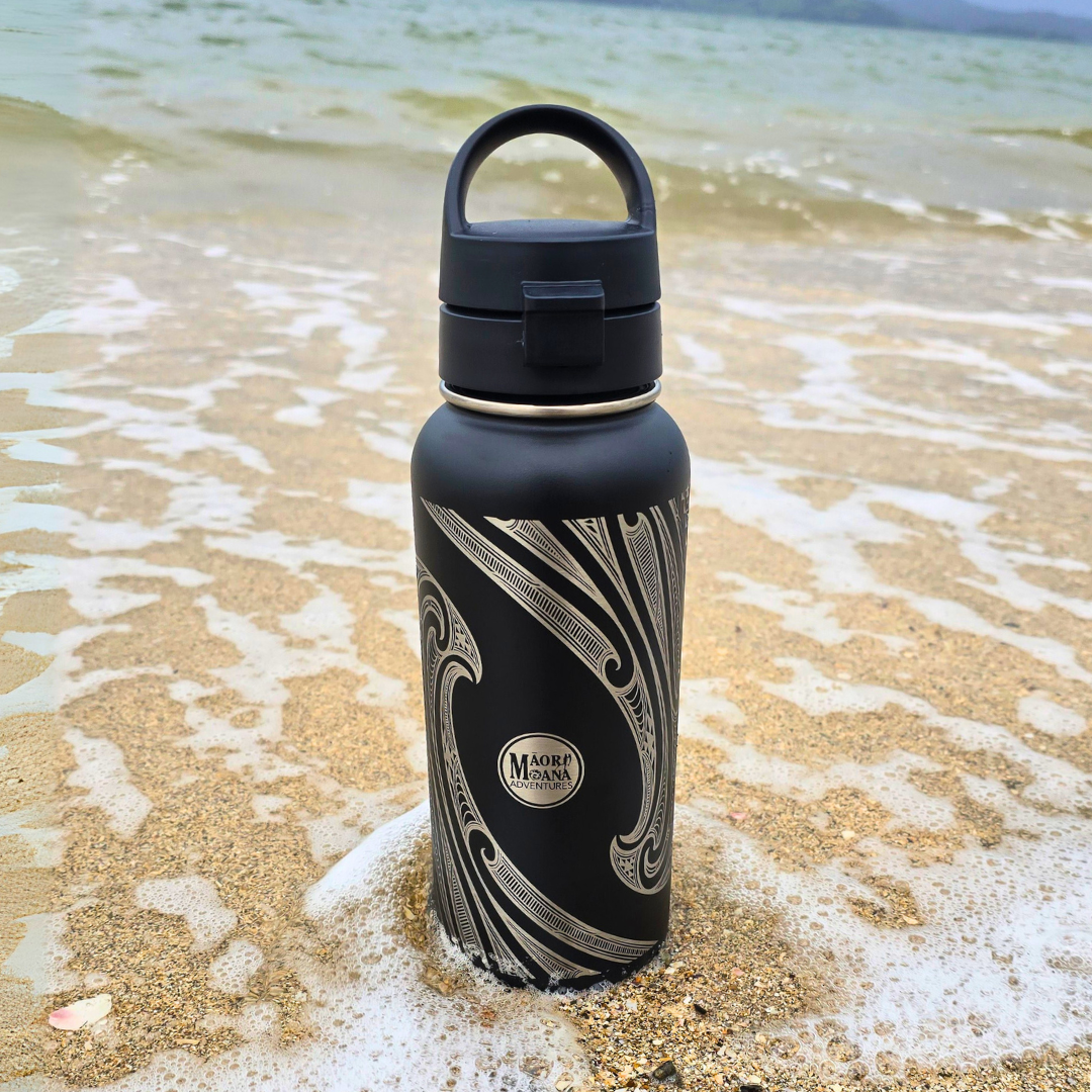 Black water bottle with MAORI patterns on a beach