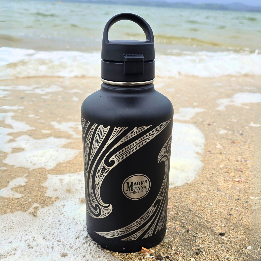 Black water bottle with MAORI patterns on a beach