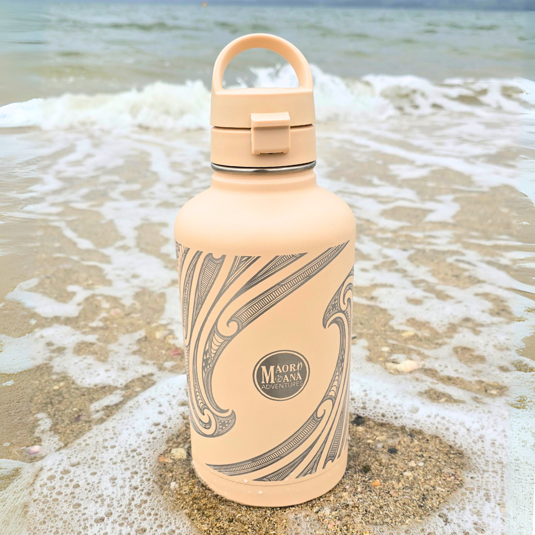Beige water bottle with maori patterns on a beach
