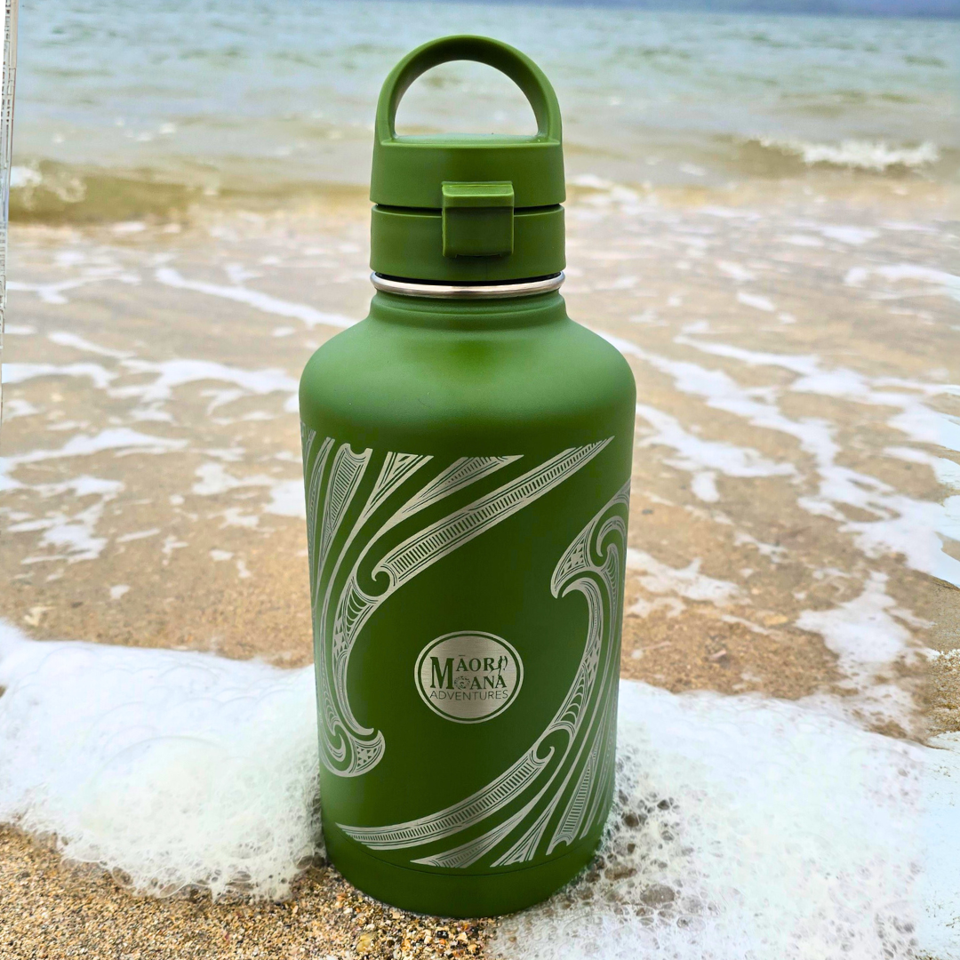 Green water bottle with māori patterns on a beach