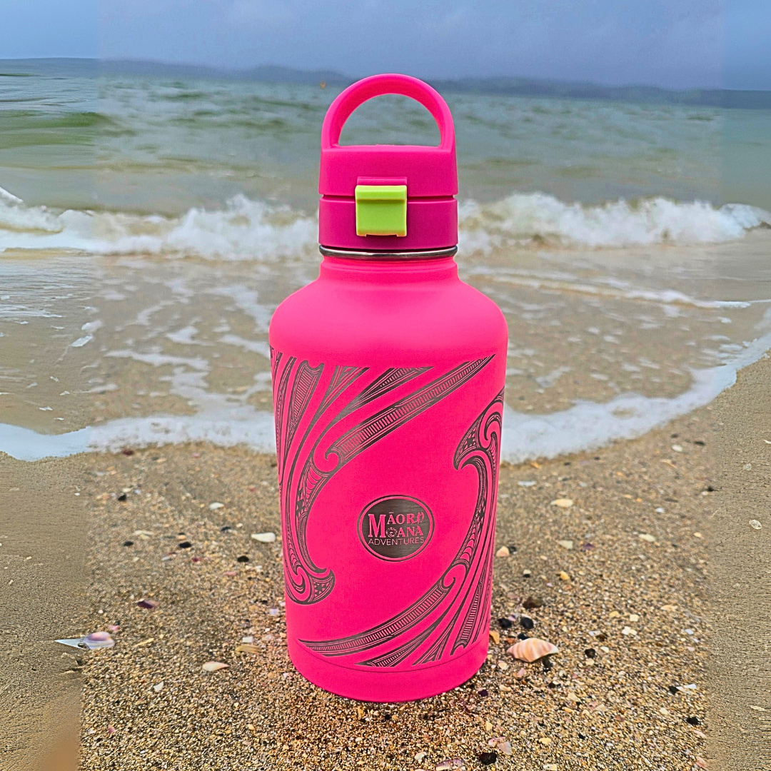 Pink water bottle with a  maori design on a beach